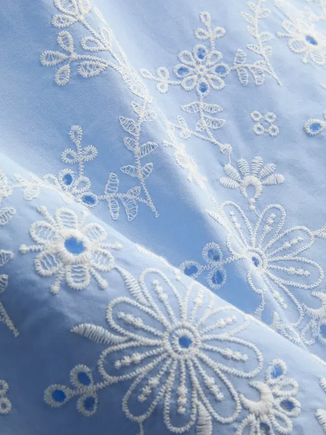 Top med broderi og bånd i siden
