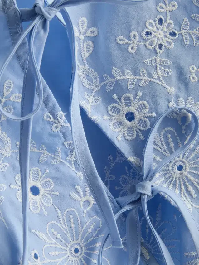 Top med broderi og bånd i siden